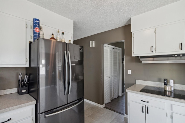 kitchen with stainless steel fridge, light hardwood / wood-style flooring, black electric cooktop, white cabinets, and a textured ceiling