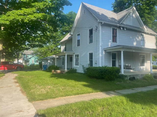 view of side of property featuring a porch and a yard