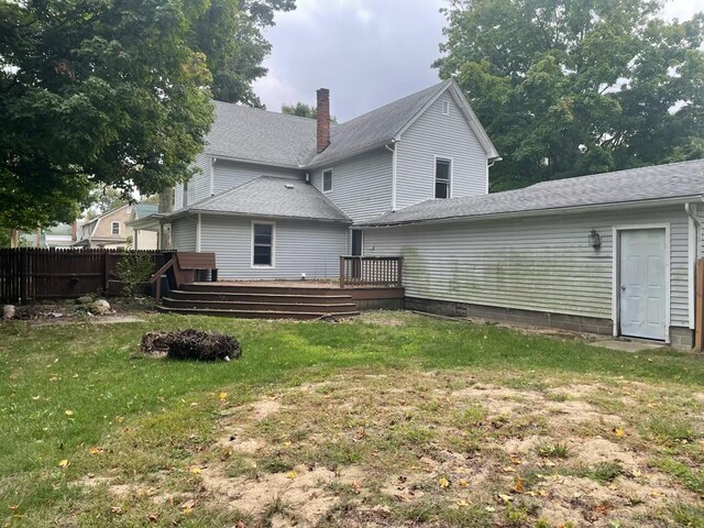 back of house with a deck and a lawn