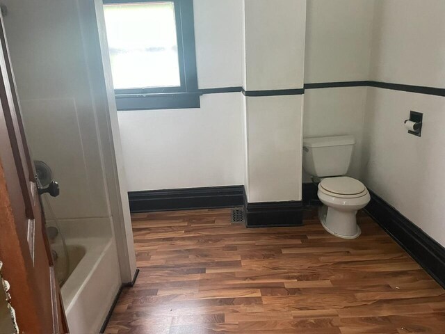 bathroom with shower with separate bathtub, hardwood / wood-style floors, and toilet