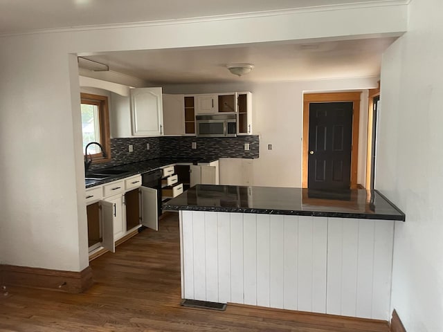 kitchen with backsplash, sink, kitchen peninsula, dark hardwood / wood-style floors, and white cabinetry