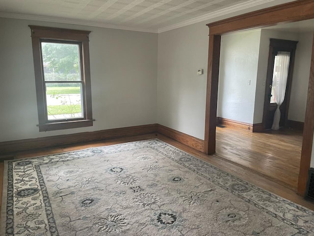 empty room featuring ornamental molding and hardwood / wood-style floors