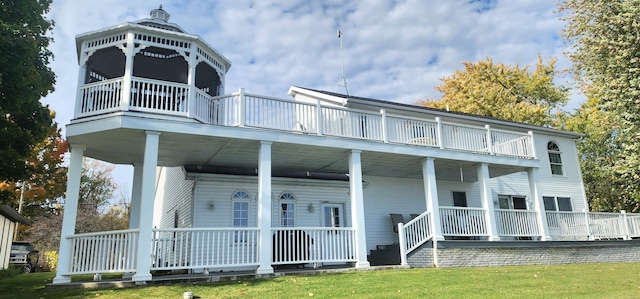 rear view of property featuring a gazebo, a yard, and a balcony