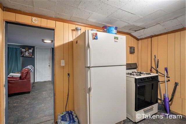 kitchen with wood walls, vaulted ceiling, and white appliances