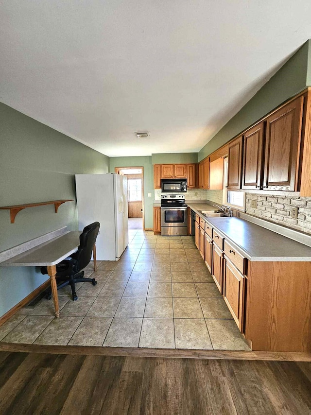 kitchen with light hardwood / wood-style flooring, black appliances, sink, and backsplash