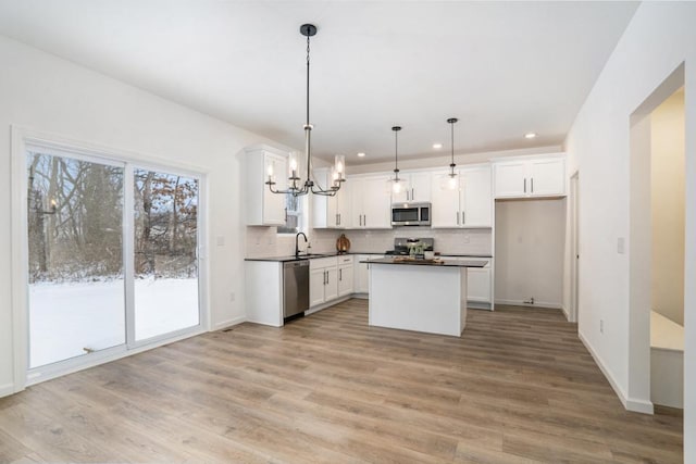 kitchen with a kitchen island, white cabinets, pendant lighting, and appliances with stainless steel finishes