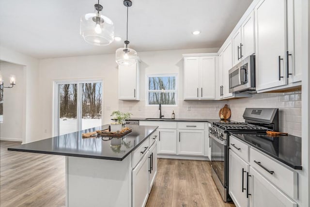 kitchen featuring white cabinets, hanging light fixtures, sink, and appliances with stainless steel finishes