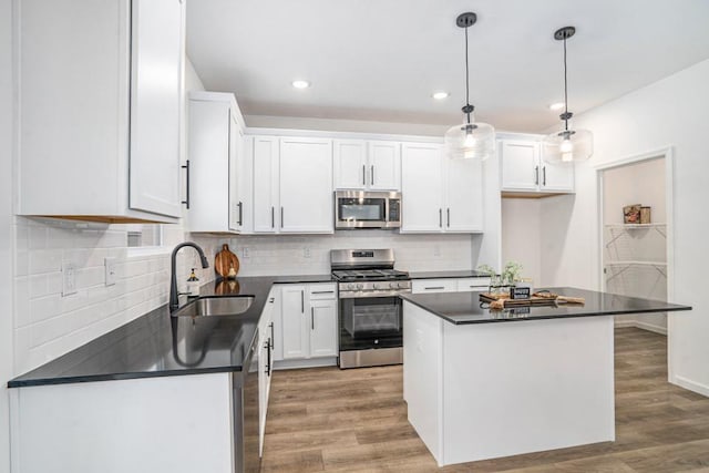 kitchen featuring white cabinetry, sink, pendant lighting, a kitchen island, and appliances with stainless steel finishes