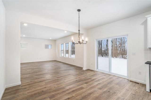 unfurnished dining area with a chandelier and wood-type flooring