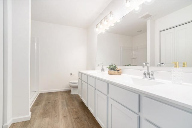 bathroom featuring a shower, vanity, hardwood / wood-style flooring, and toilet