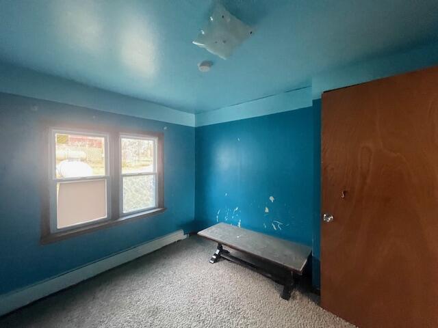 unfurnished bedroom featuring carpet floors and a baseboard heating unit