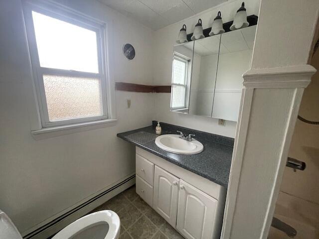 bathroom with toilet, vanity, and a baseboard heating unit