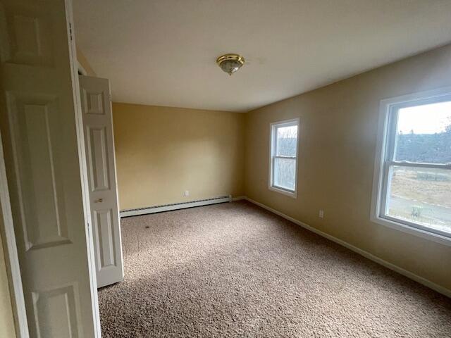 empty room with carpet flooring and a baseboard radiator