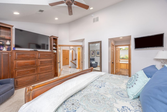 bedroom featuring ceiling fan, light colored carpet, ensuite bathroom, and high vaulted ceiling