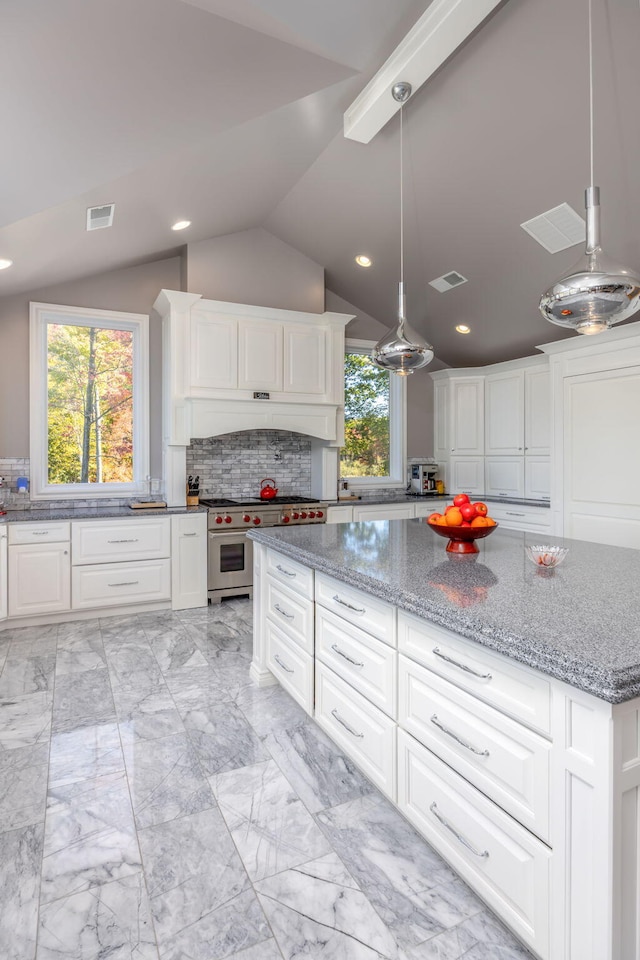 kitchen with decorative light fixtures, light stone counters, lofted ceiling, premium range hood, and white cabinetry