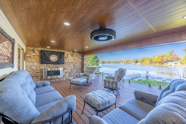 exterior space featuring wood-type flooring, plenty of natural light, wooden ceiling, a water view, and an outdoor stone fireplace