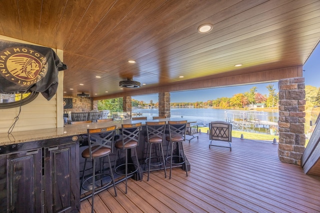 wooden deck featuring an outdoor bar, a water view, and ceiling fan