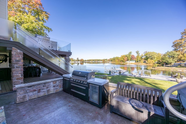 view of patio featuring a water view, a grill, an outdoor kitchen, and a dock