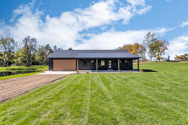 view of front facade with a front lawn, a water view, covered porch, and a garage