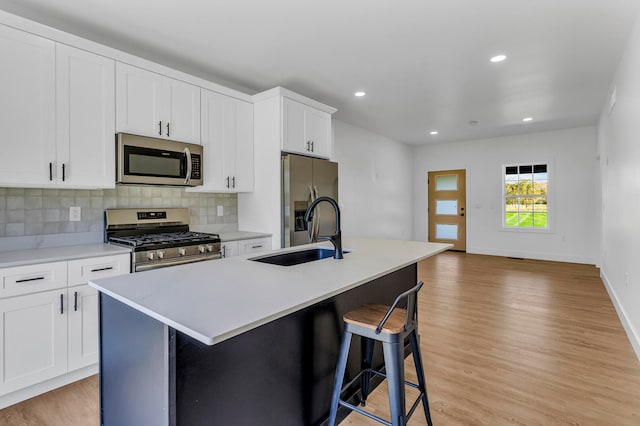 kitchen with a center island with sink, stainless steel appliances, and light wood-type flooring