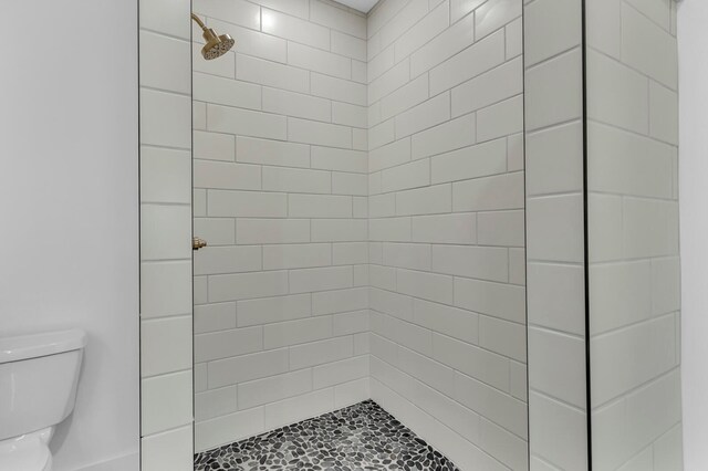 bathroom featuring a tile shower and toilet