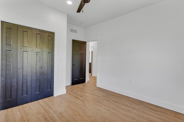 unfurnished bedroom featuring a closet, light hardwood / wood-style flooring, and ceiling fan