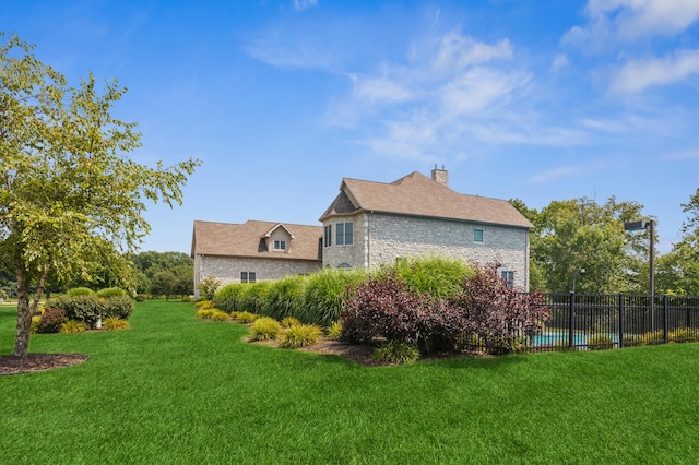 view of side of home with a fenced in pool and a yard