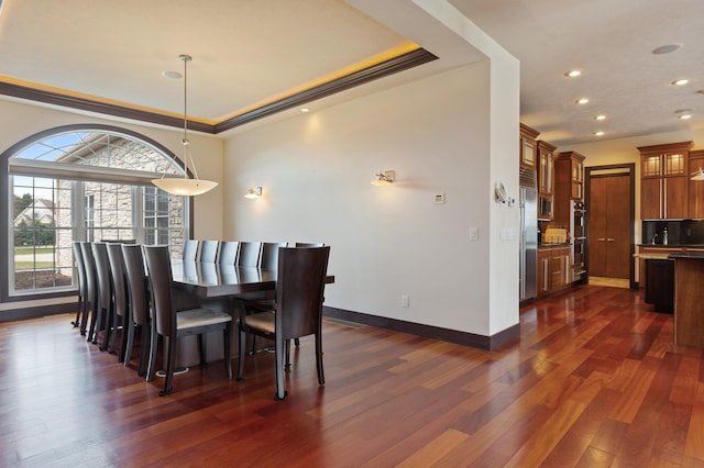 dining space featuring ornamental molding, a tray ceiling, and dark hardwood / wood-style floors