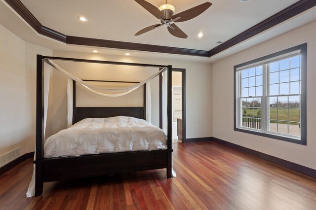 bedroom with ornamental molding, a tray ceiling, hardwood / wood-style floors, and ceiling fan