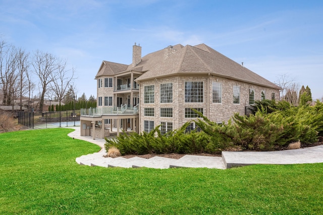 back of house featuring a patio, a balcony, and a lawn