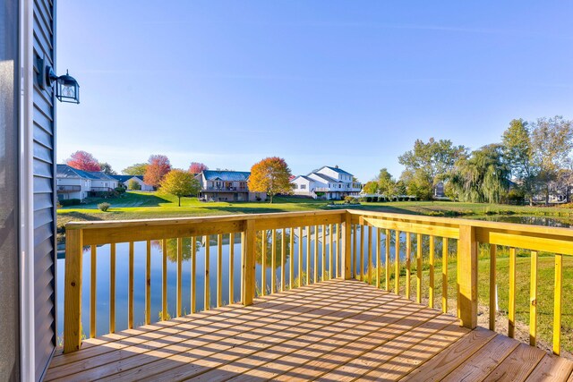 wooden terrace featuring a lawn and a water view