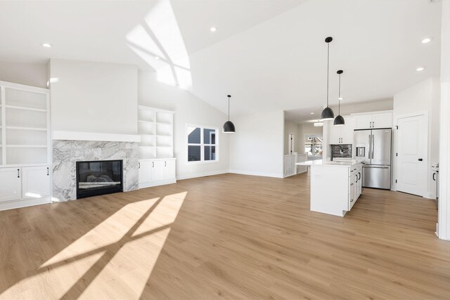 unfurnished living room featuring lofted ceiling, light wood-type flooring, and a fireplace