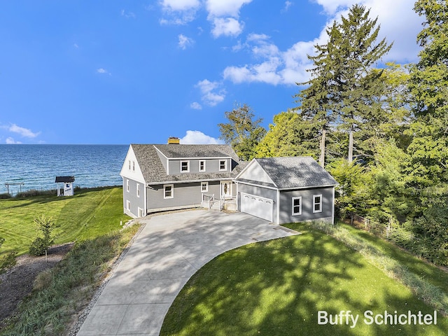 3163 N Scenic Dr, Muskegon, MI 49445 - view of front facade with an attached garage, concrete driveway, a front lawn, a chimney, and a water view