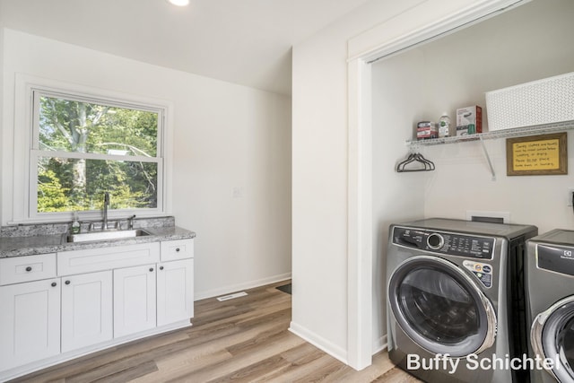 3163 N Scenic Dr, Muskegon, MI 49445 - clothes washing area with a sink, light wood-type flooring, visible vents, washing machine and clothes dryer, and baseboards