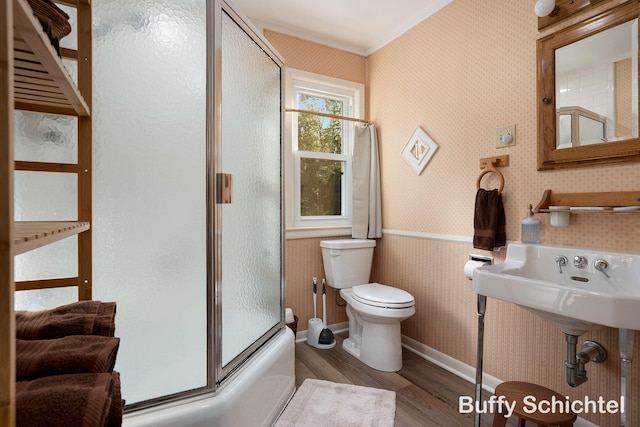 3163 N Scenic Dr, Muskegon, MI 49445 - bathroom featuring toilet, wood finished floors, combined bath / shower with glass door, baseboards, and wallpapered walls