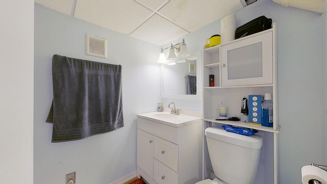 bathroom with toilet, a paneled ceiling, and vanity