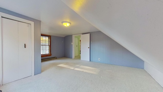 additional living space featuring baseboard heating, light colored carpet, and vaulted ceiling