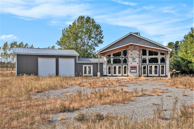 back of property featuring a garage, an outbuilding, and french doors