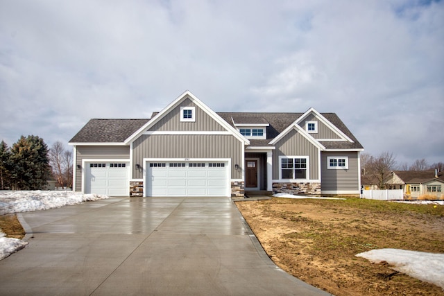 craftsman-style home with an attached garage, a shingled roof, driveway, stone siding, and board and batten siding