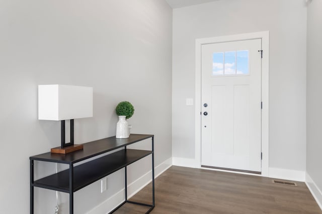 foyer entrance featuring baseboards, visible vents, and wood finished floors