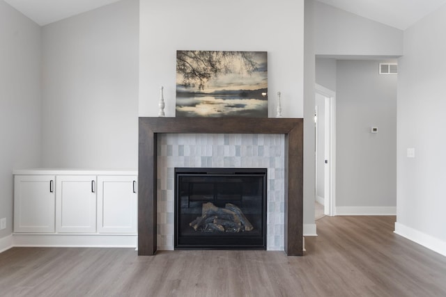 interior details featuring visible vents, a fireplace, baseboards, and wood finished floors