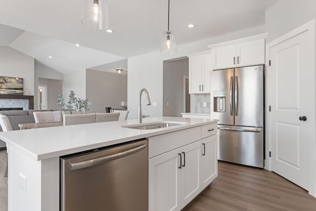 kitchen with stainless steel appliances, an island with sink, a sink, and light countertops