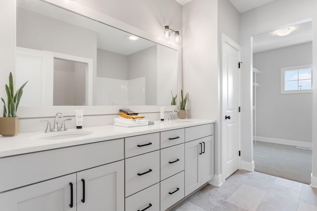 full bathroom featuring a sink, a spacious closet, baseboards, and double vanity