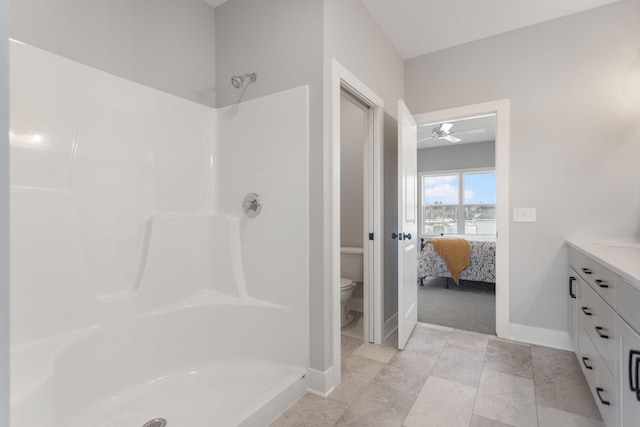 ensuite bathroom featuring baseboards, toilet, ensuite bathroom, walk in shower, and vanity