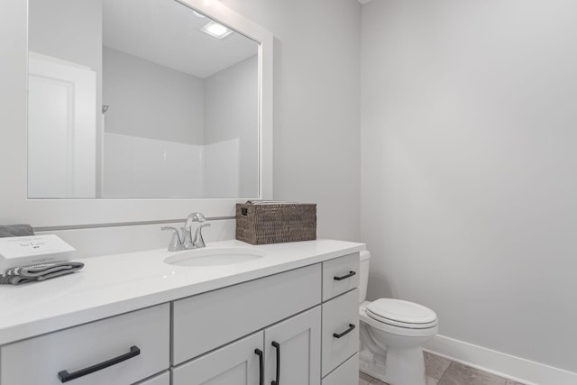 full bath featuring toilet, vanity, and baseboards