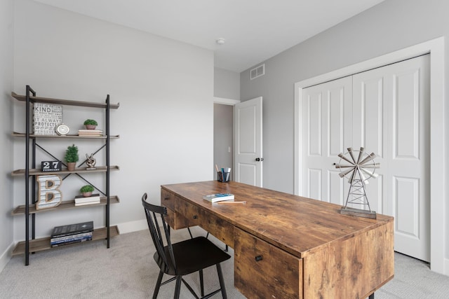 office featuring baseboards, visible vents, and light colored carpet