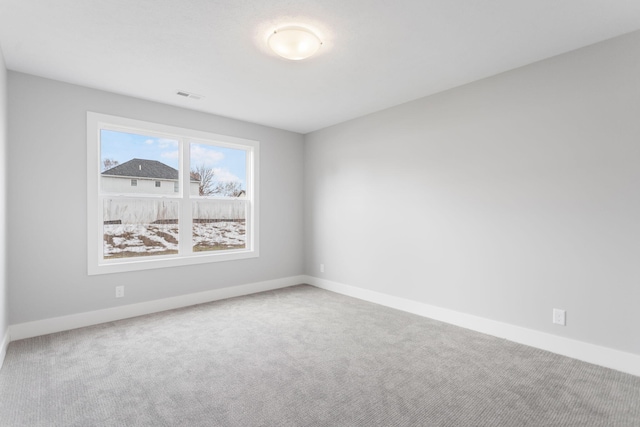 carpeted spare room with visible vents and baseboards