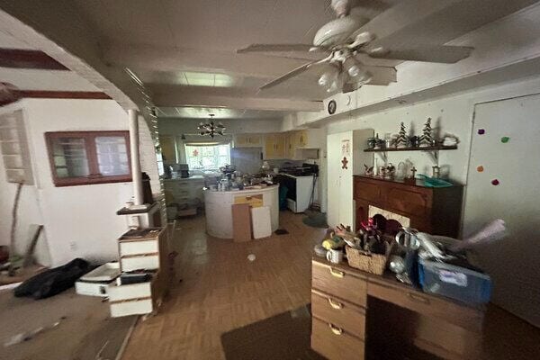 kitchen featuring wood-type flooring, a kitchen island, ceiling fan with notable chandelier, and stainless steel refrigerator