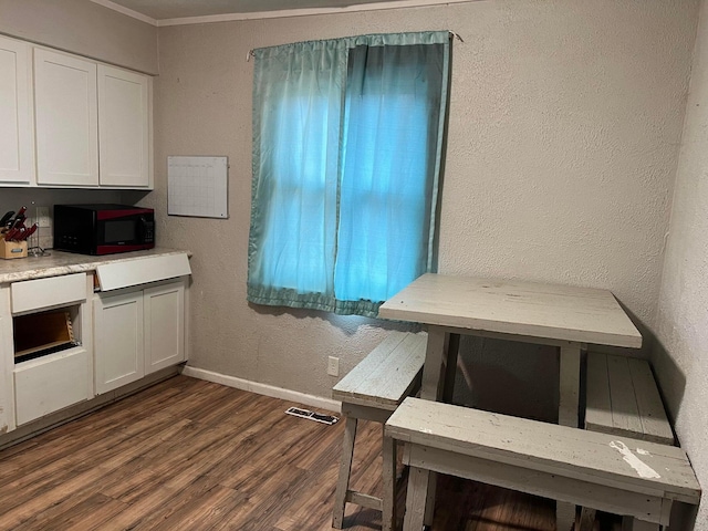 dining area with crown molding and dark wood-type flooring