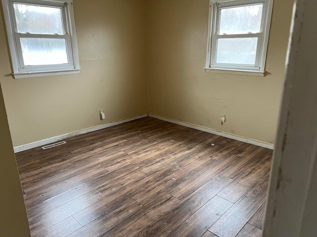 spare room with plenty of natural light and dark hardwood / wood-style flooring